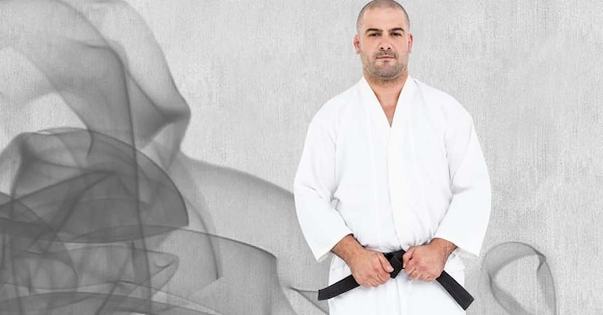 Mężczyzna w kimono z czarnym pasem przed szarym tłem