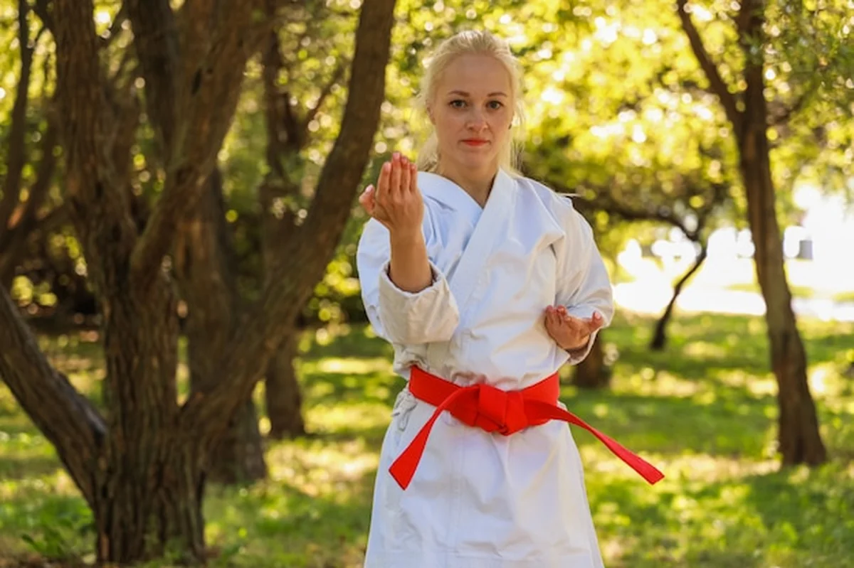 Młoda kobieta w kimono trenuje karate w parku - czerwony pas
