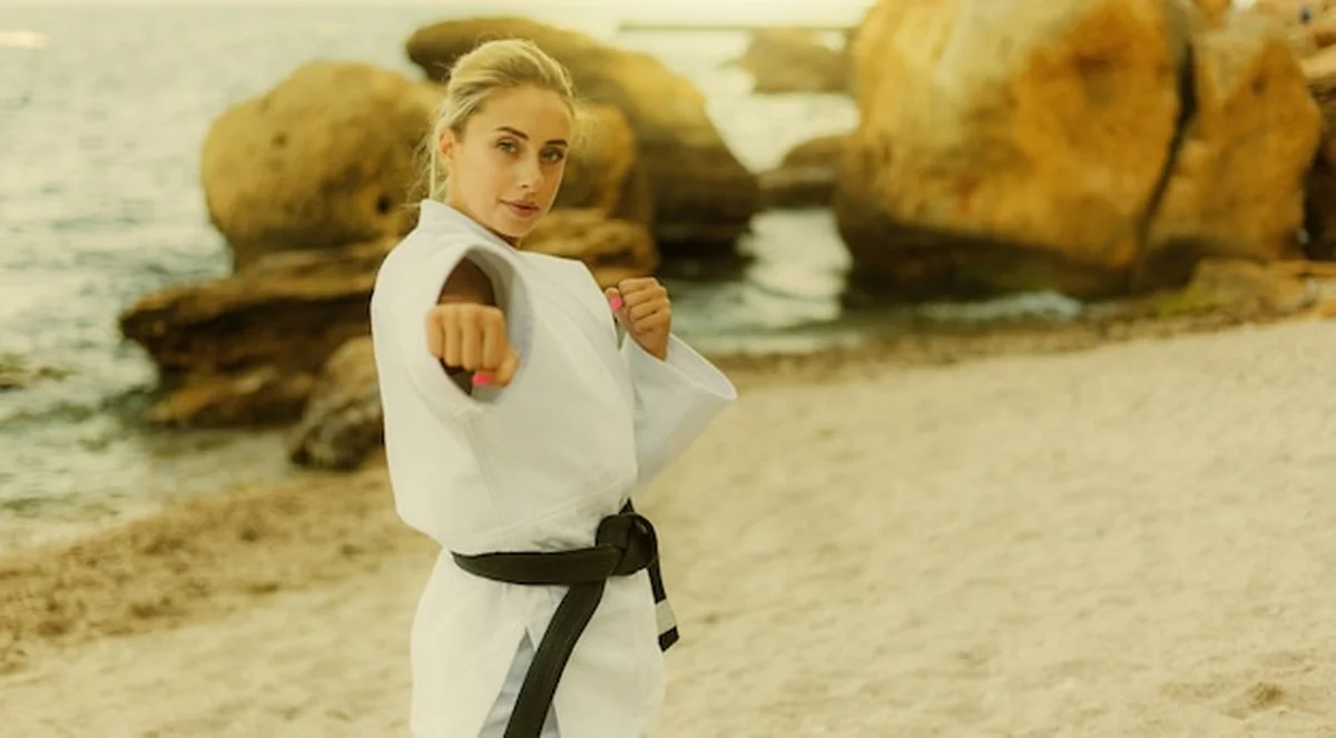 Artystka sztuk walki w białym kimonie na plaży